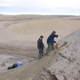 Two researchers digging into a dune at Kap København.